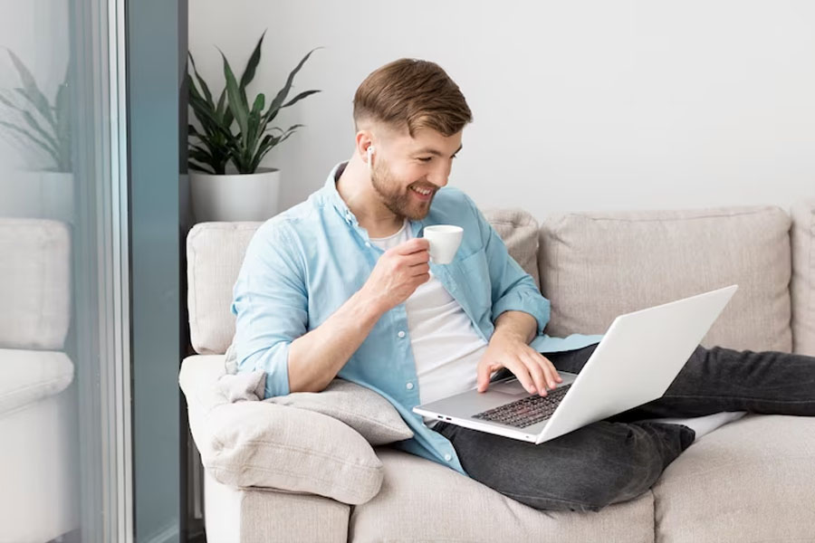 Мужчина пьет кофе и смотрит в ноутбук