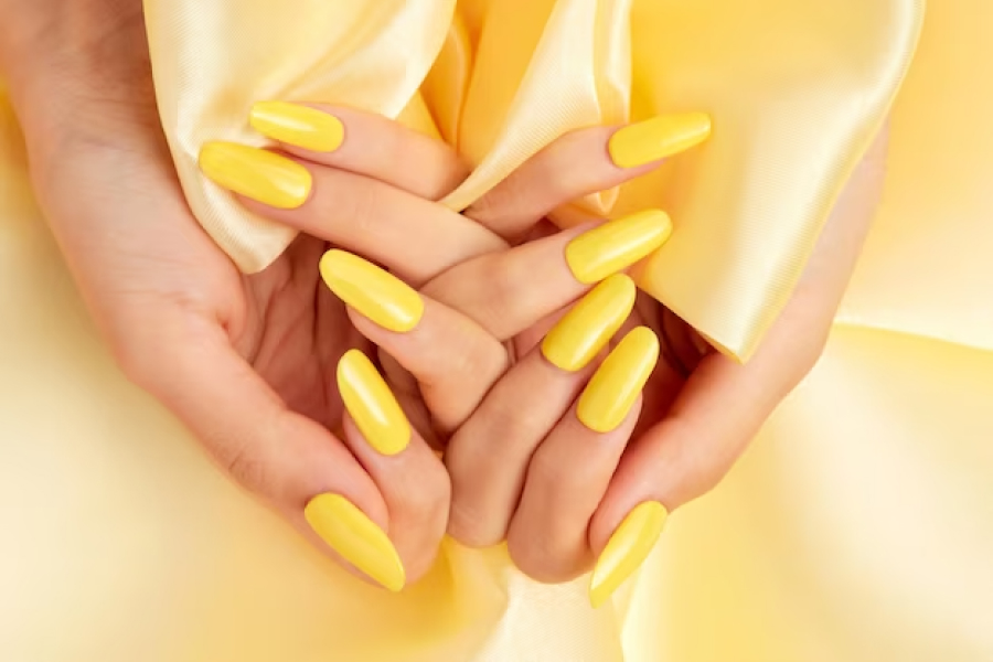 Жёлтые ногти на фоне жёлтой шелковистой ткани