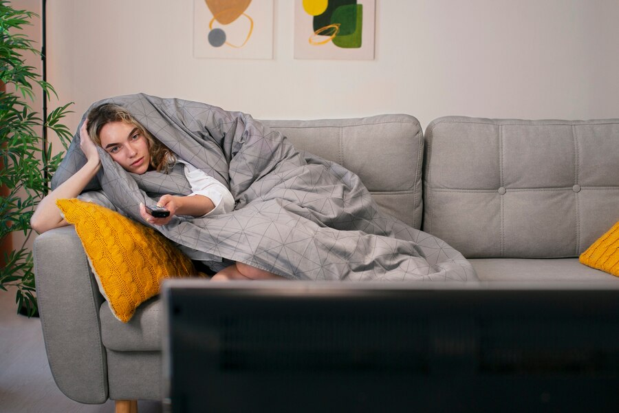 Девушка под одеялом смотрит телевизор