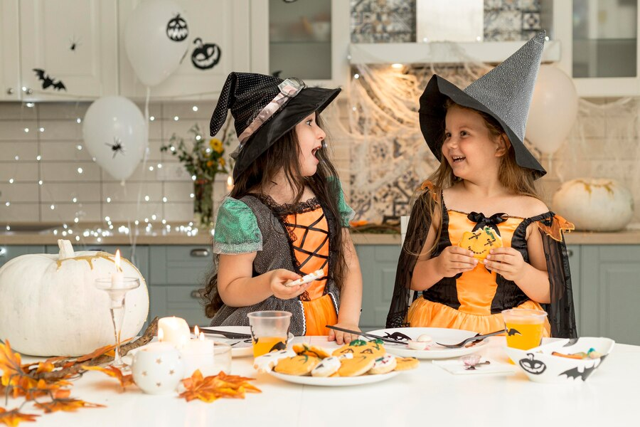 Девочки в костюмах ведьм едят печенье