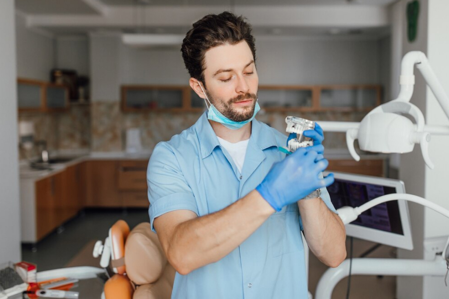 Стоматолог держит протез челюсти